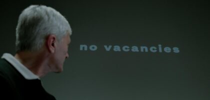 senior man looking at inscription displayed on wall saying no vacancies