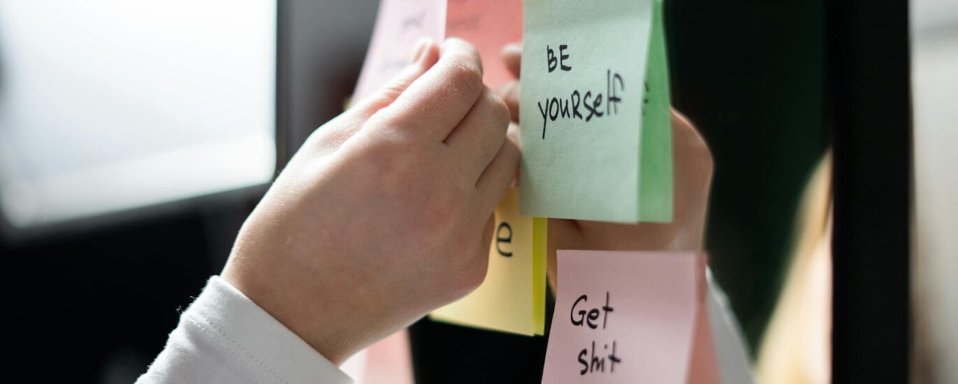 person holding white and pink sticky notes